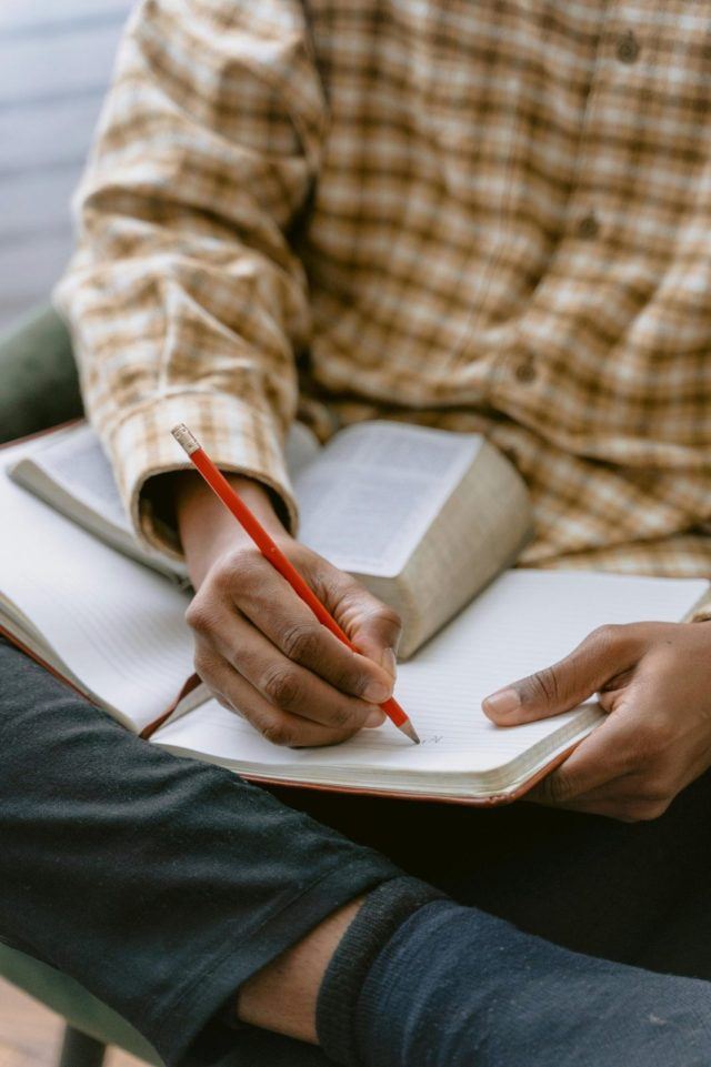 Person taking notes in a notebook representing self-awareness and progress